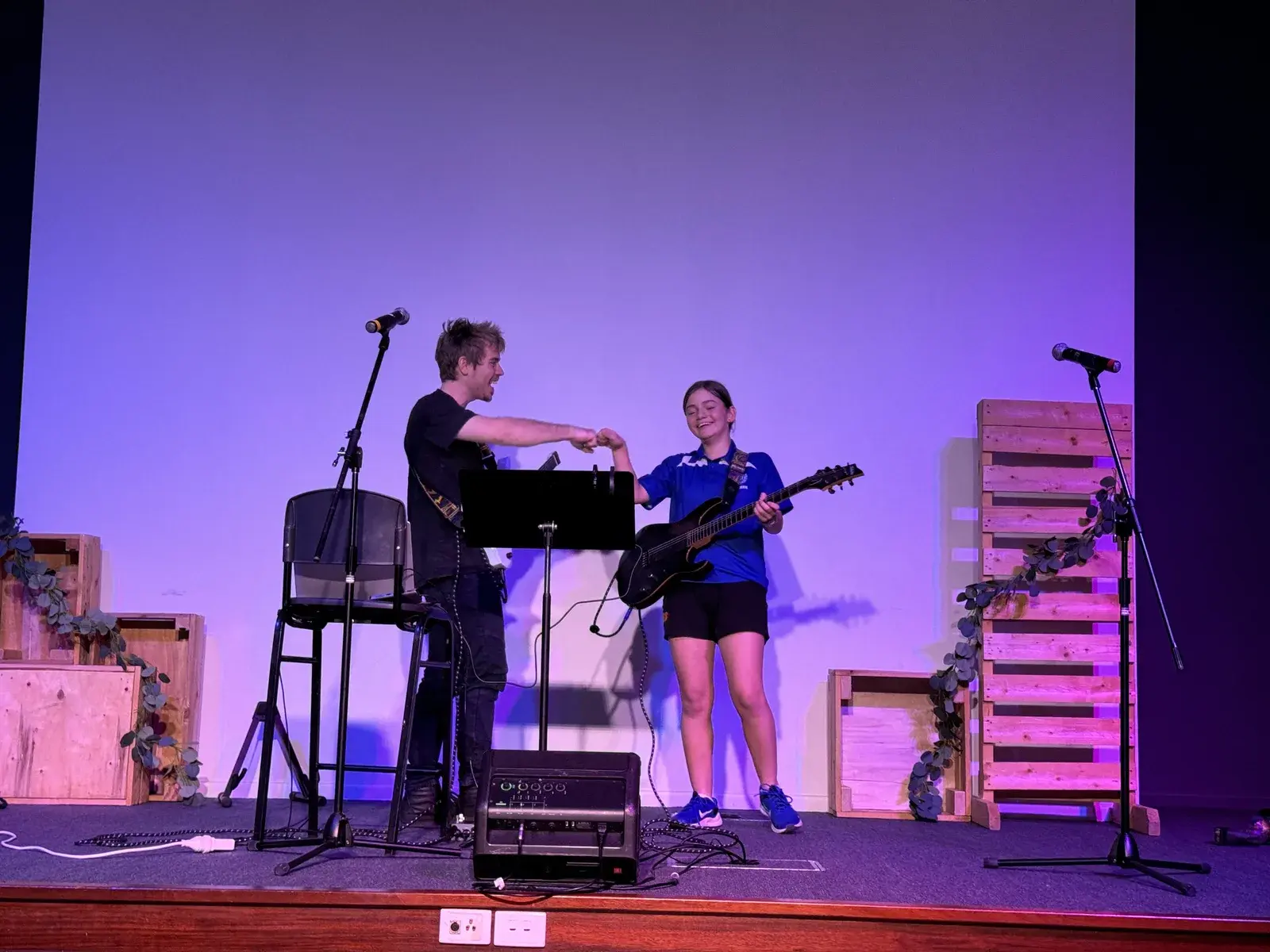 Damien Hill celebrating with a guitar student on stage after a student concert in Townsville
