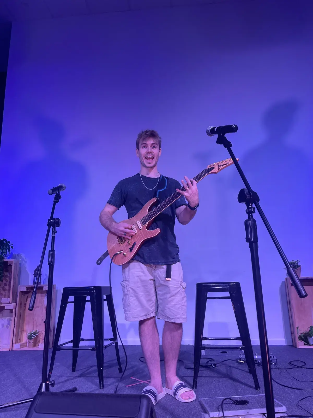 Damien Hill setting up on stage with an electric guitar before a student concert in Townsville